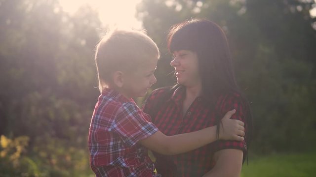 happy family mother's day funny the nature slow motion video teamwork outdoors. mom girl holds son boy in arms smiling sunlight lifestyle cute video care. mother andson circling friendly cuddle family