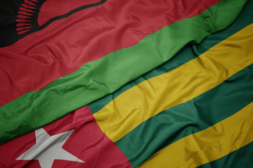 waving colorful flag of togo and national flag of malawi.