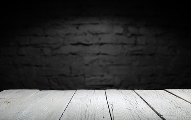 Wood table in front of rustic brick wall blur background with empty copy space on the table for product display mockup. Retro design montage presentation.