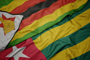 waving colorful flag of togo and national flag of zimbabwe.