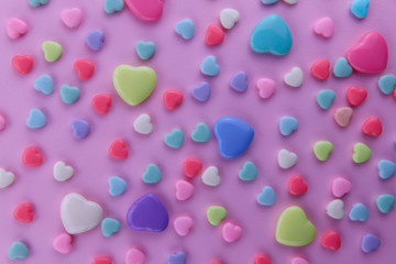 Background Valentine's Day. Yellow, blue, red and white hearts of different sizes on a pink background. Top view, close-up, cropped shot, horizontal.