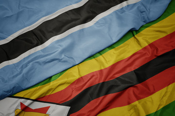 waving colorful flag of zimbabwe and national flag of botswana.