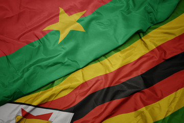waving colorful flag of zimbabwe and national flag of burkina faso.