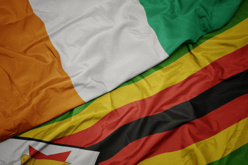 waving colorful flag of zimbabwe and national flag of cote divoire.