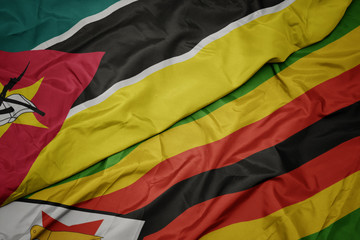 waving colorful flag of zimbabwe and national flag of mozambique.