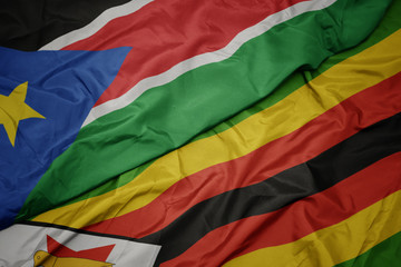 waving colorful flag of zimbabwe and national flag of south sudan.