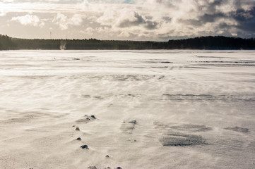 Snow runs over the ice of the lake.