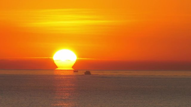 Awesome sunrise over sea with boats at dawn, slow motion