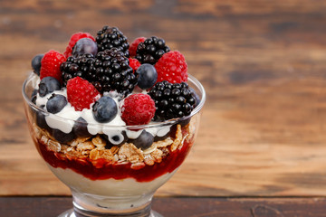 Portion of layer dessert with fresh fruits and muesli.
