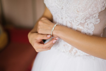 Obraz na płótnie Canvas Bride fastens bracelet on her hand, close-up