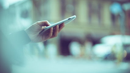 asian woman using smartphone with blurred city street as background