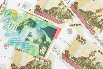 A close up image of a twenty shekel bank note from Israel on a background of Russian one hundred ruble bills in macro
