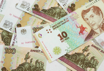 A close up image of a ten peso bank note from Argentina on a bed of Russian one hundred ruble bank notes in macro
