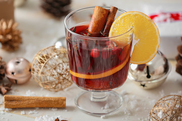 Glass of tasty mulled wine and Christmas decor on table