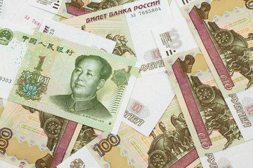 A green, one Chinese yuan bank note close up in macro with Russian one hundred ruble bills