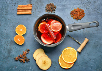 Pot of tasty mulled wine and ingredients on color background