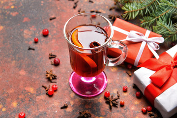 Glass cup of tasty mulled wine, Christmas gifts and fir branches on table