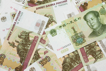 A green, one Chinese yuan bank note close up in macro with Russian one hundred ruble bills