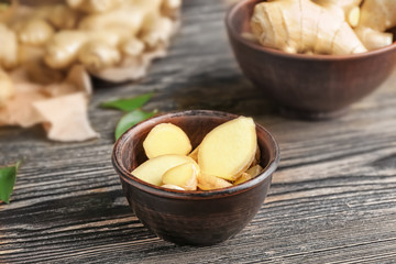 Bowl with fresh ginger on wooden table