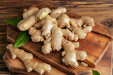 Boards with fresh ginger on wooden table