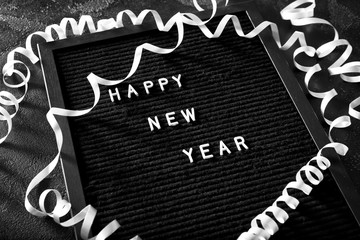 Board with text HAPPY NEW YEAR on dark background