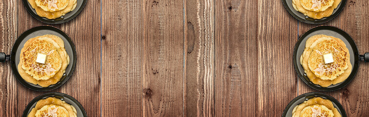 Frying pans with hot delicious pancakes on natural wooden table. Pancake week. Panoramic banner.