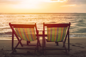 two blank beach bed chair set on the beach with sun twilight sky background.