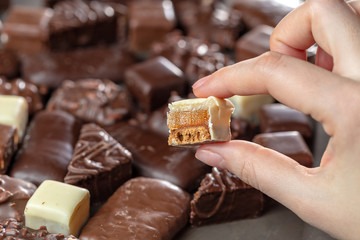 Assortment of chocolate handmade. Female hand holds tasty marmalade candy in white chocolate.
