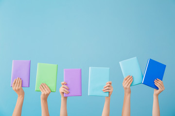 Female hands with books on color background