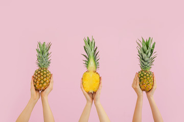 Hands with juicy pineapples on color background