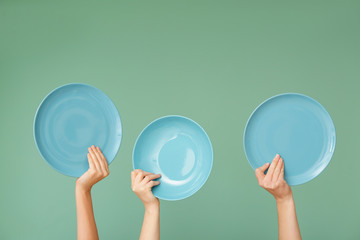 Hands with clean plates on color background