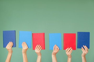 Female hands with books on color background