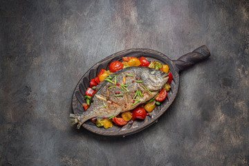 Fried fish with vegetables on cutting board, copy space