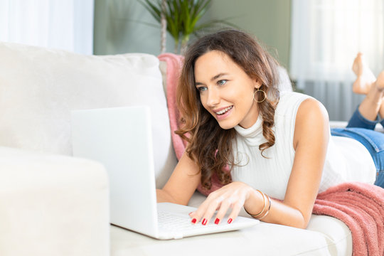 Young woman using laptop on sofa.