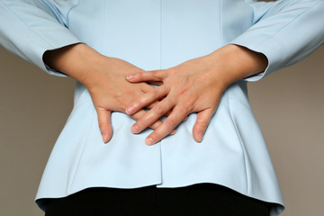Back pain, woman in office suit suffering from backache. Female hands holding lower back, kidney or spine disease
