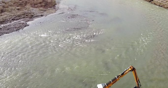 Backward view Water escavator working inside Arno river near Sieci town, Pontassieve, to avoid another Florence disaster flood afer latest November rainy long season. Sunny day Winter, Tuscany. Italy
