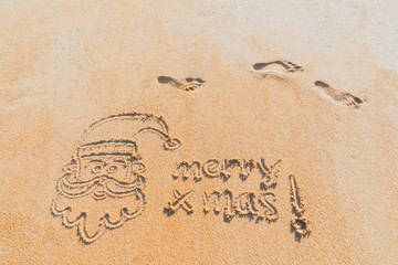 Fototapeta premium Concept Christmas on the beach Tropical design made in Phuket, Thailand Write the alphabet on the sand background Taken from real locations.