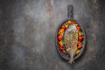 Fried whole fish with vegetables on cutting board, copy space