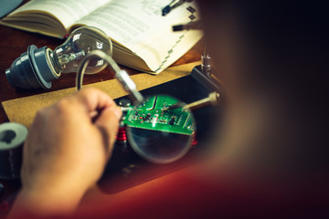 Hands of man holding solder iron  soldering the pin on electronics circuit board,  DIY hobbies and...