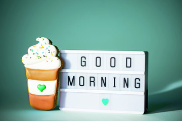 The inscription good morning on a light box with gingerbread on a mint background