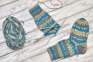 Knitting process of children's socks on a light wooden background