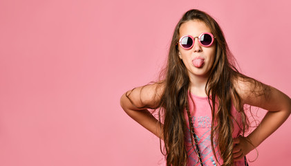 Portrait of young plus size girl with long hair in stylish summer casual clothing and round sunglasses showing tongue