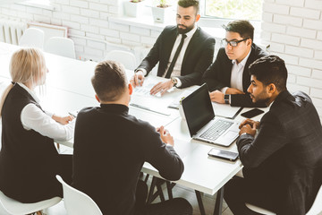 A team of young businessmen working and communicating together in an office. Corporate businessteam and manager in a meeting.