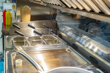 Kitchen facilities in the cafe. Industrial machinery. Fast food company. Fryers in the kitchen. Appliances for cooking. Stainless steel kitchen appliances. Working in a cafe.