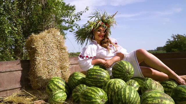 Cute plus size girl in folk dress and circlet posing in trailer with watermelons