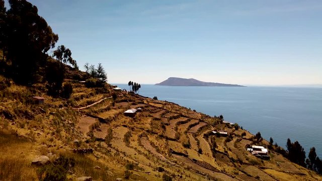 Cultivation terraces of the Inca period in Taquile Island. A blue sky mixes on the horizon with color water. Peru