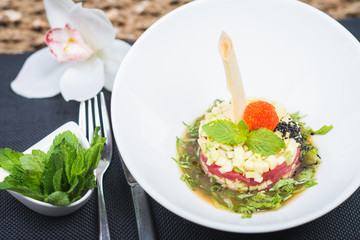 Classic traditional tartar salad laid in a round shape, stylish serving in an oriental style table in a restaurant.
