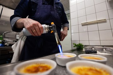 chef preparing creme brulee with bleberries in commercial kitchen