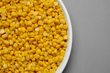 canned corn in white plate top view. grey background	