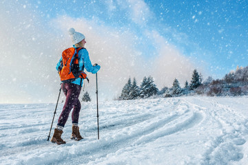 Happy woman tourist walking on the snowy trek on the peak of mou